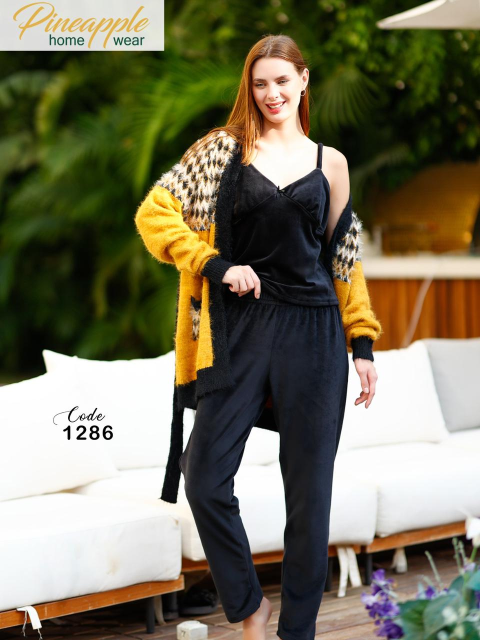 Woman wearing a black outfit with a yellow cardigan in an outdoor setting, with 'Pineapple Home Wear' branding.