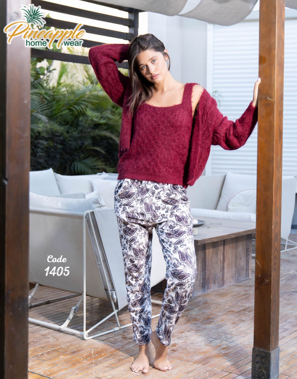 Woman wearing a red sweater and patterned pants standing in a modern living room.