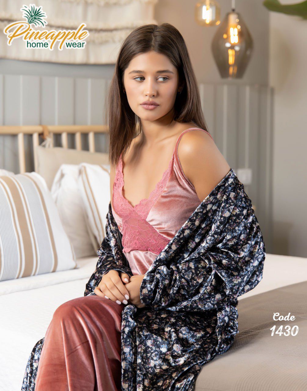 Woman sitting on a couch wearing a pink top and patterned robe with 'Pineapple Home Wear' branding.
