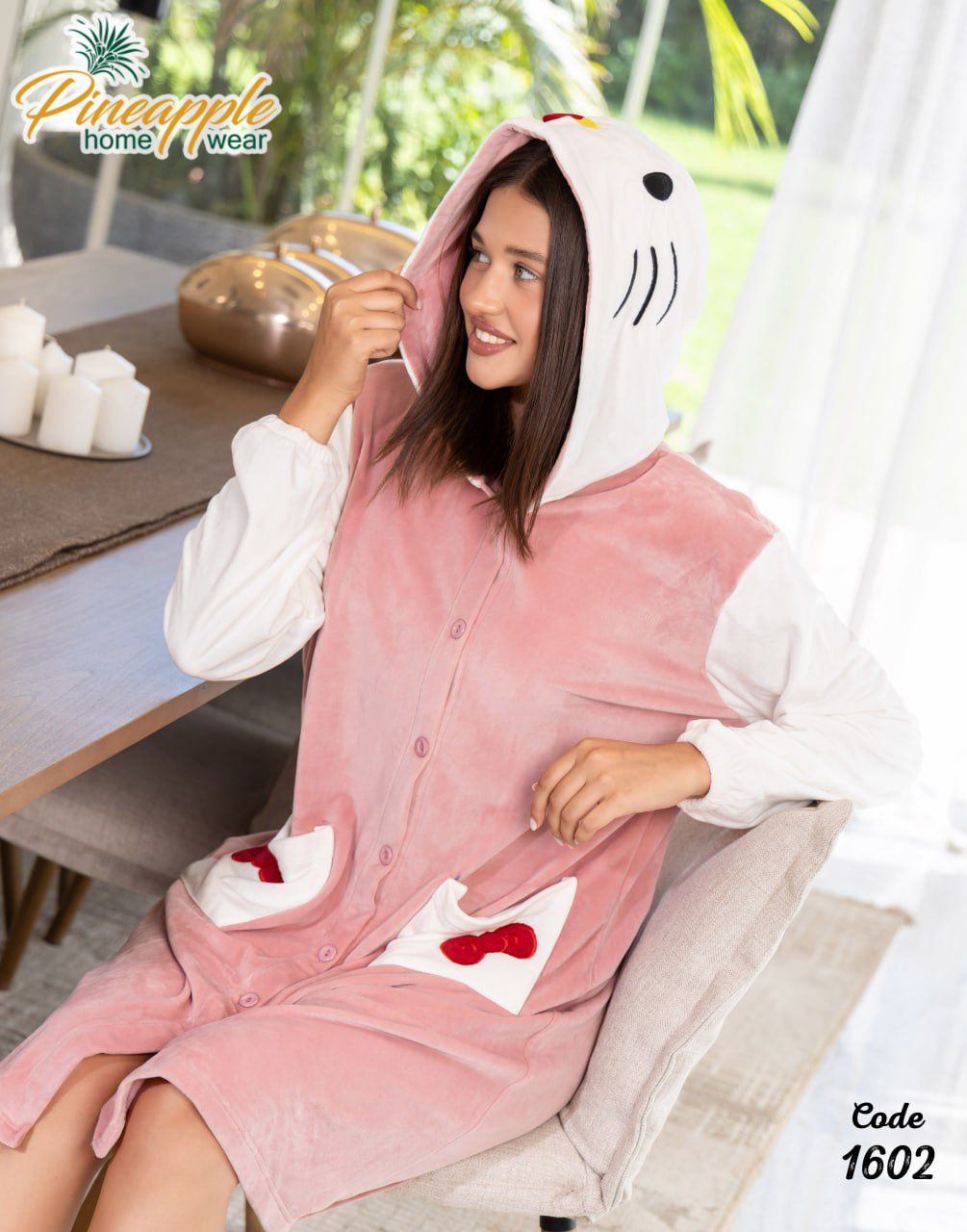 Woman wearing a pink shark-themed robe in a home setting with 'Pineapple Home Wear' branding.