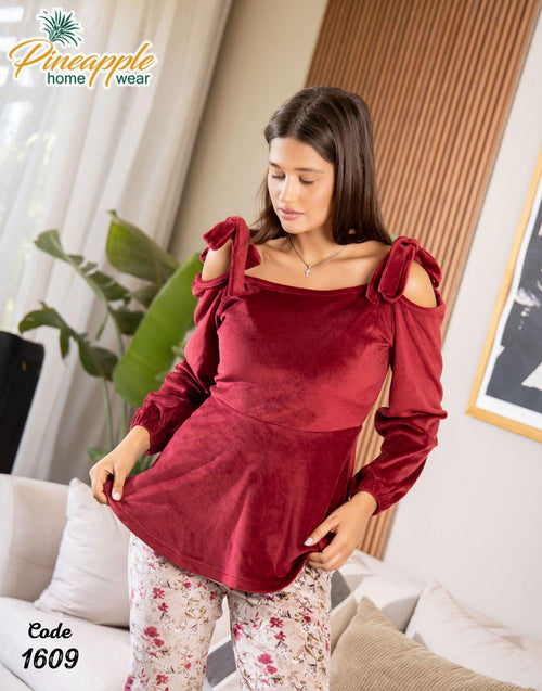Woman wearing a red top and floral pants in a living room setting with 'Pineapple Home Wear' branding.