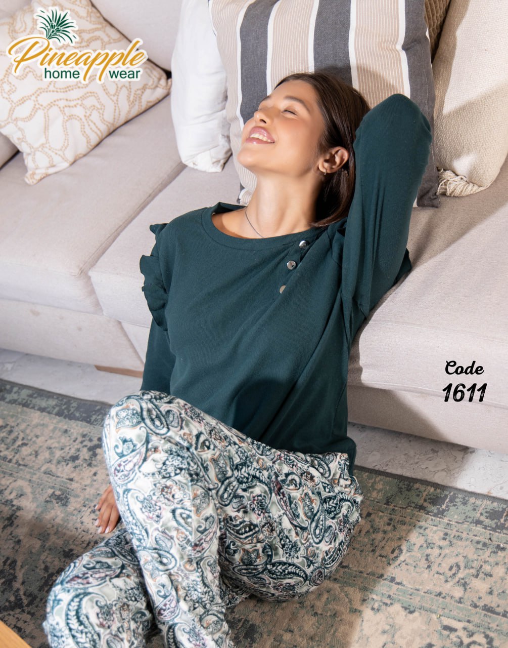 Woman in teal top and patterned pants sitting on a couch with 'Pineapple Home Wear' branding.
