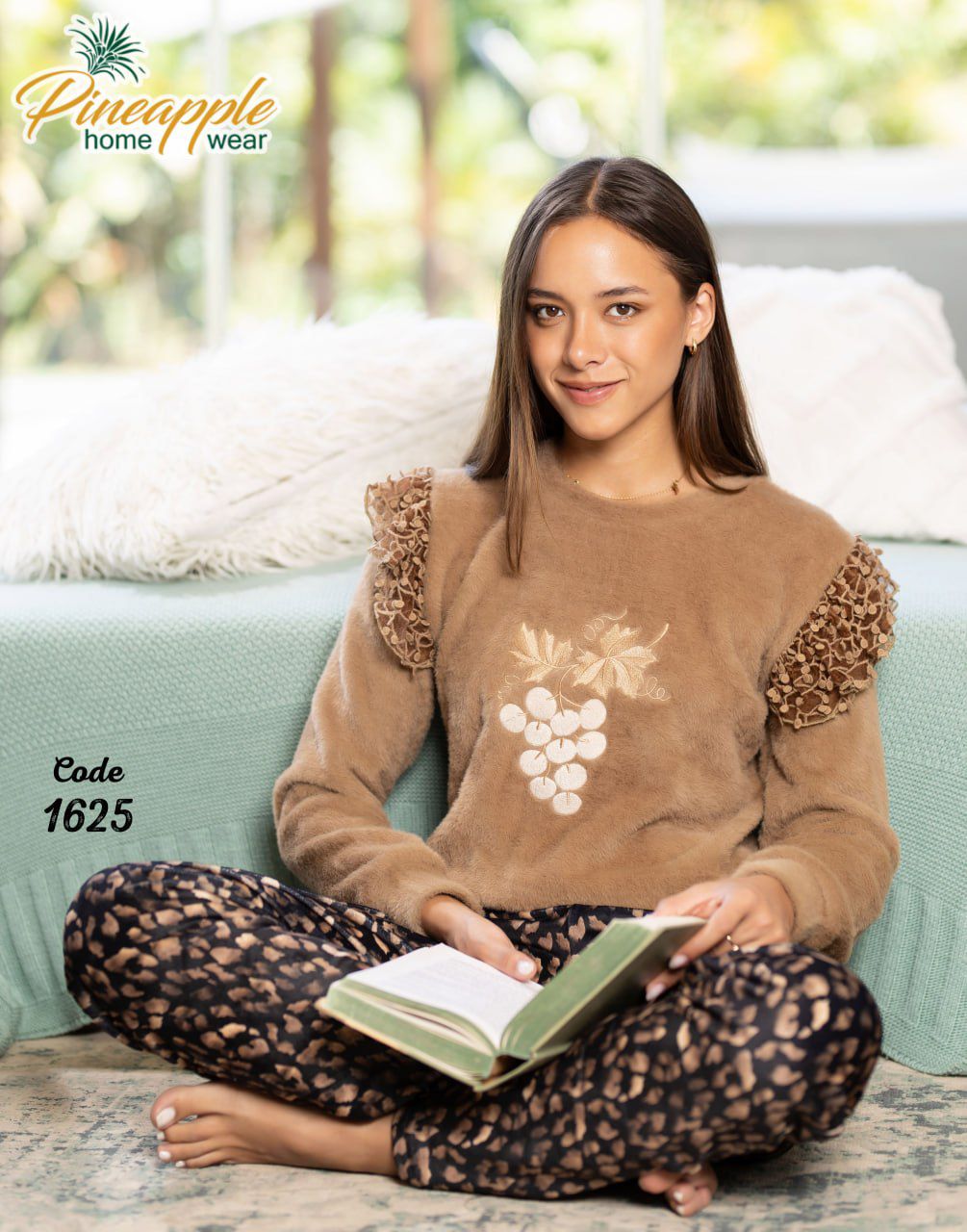 Woman wearing a brown sweater and leopard print pants sitting on a couch with a book, branded 'Pineapple Home Wear'.