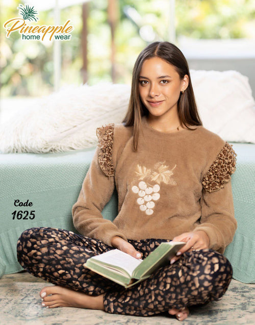Woman wearing a brown sweater and leopard print pants sitting on a couch with a book, branded 'Pineapple Home Wear'.