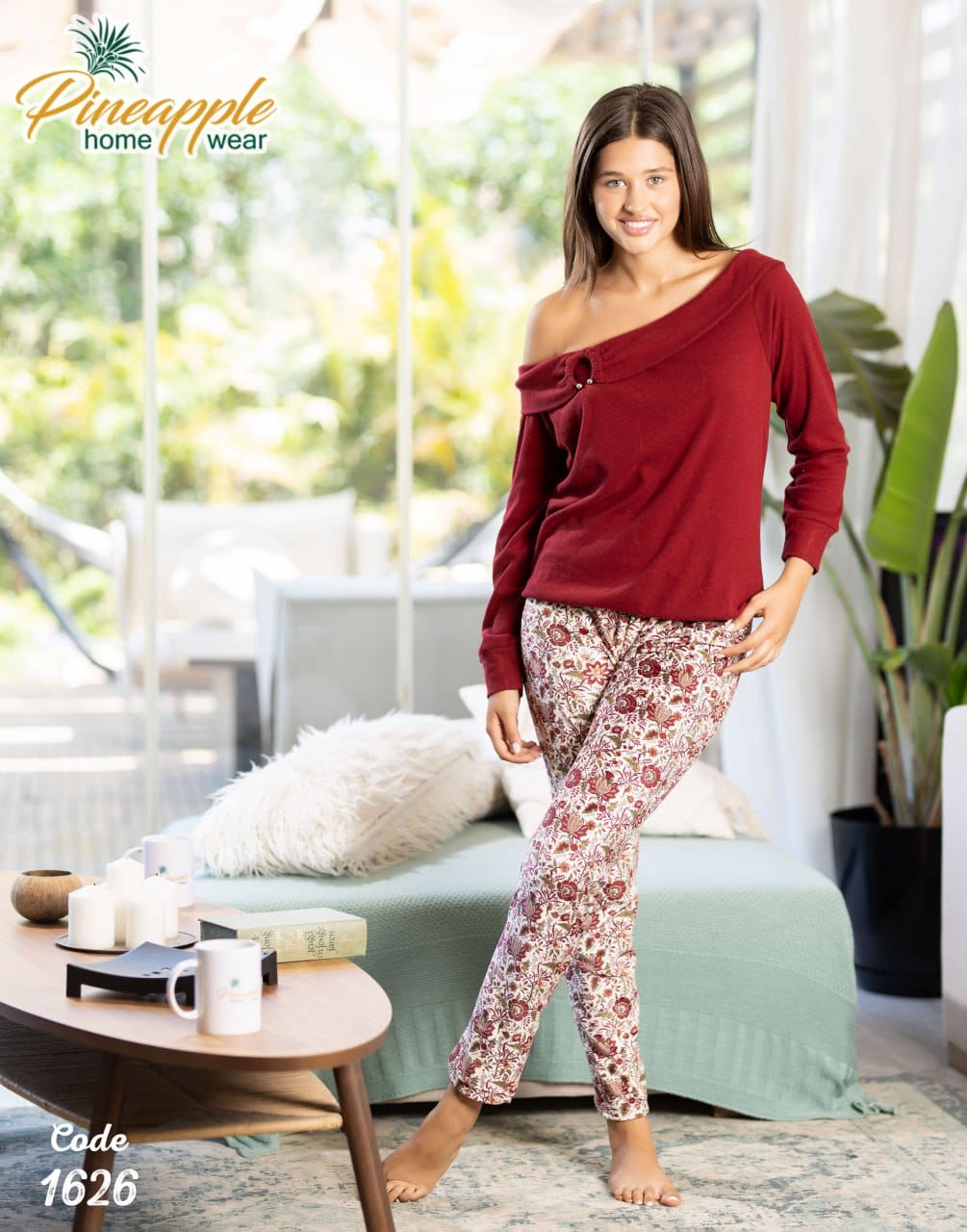 Woman wearing a red top and floral pants in a living room setting with 'Pineapple Home Wear' branding.