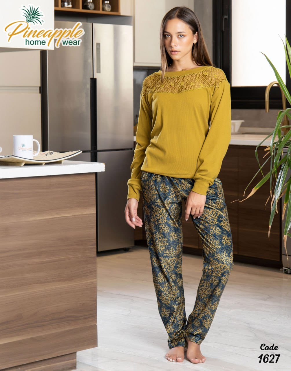 Woman wearing a mustard yellow top and patterned pants in a kitchen setting with 'Pineapple Home Wear' branding.