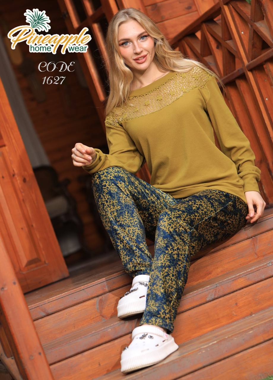 Woman sitting on wooden steps wearing a yellow sweater and patterned pants, with 'Pineapple Home Wear' branding.