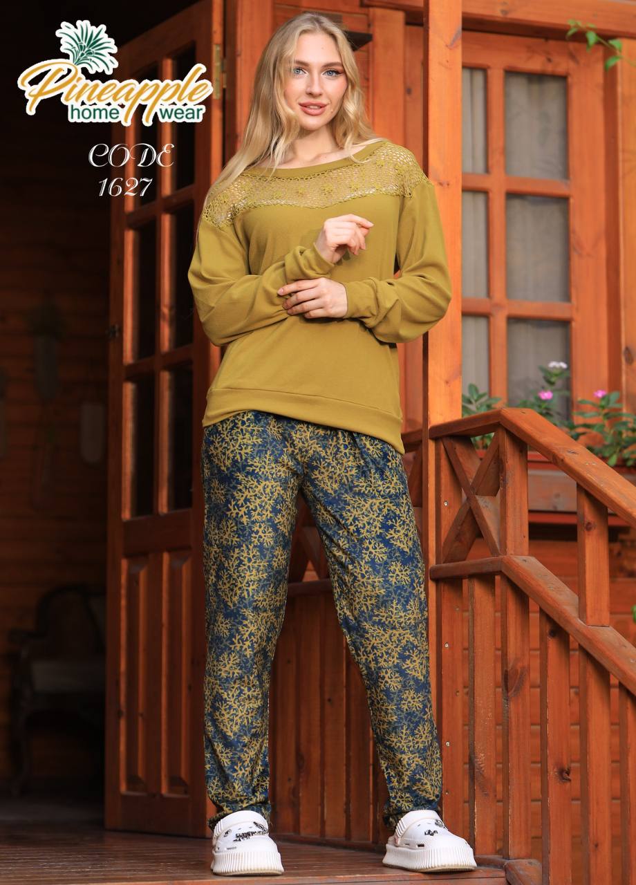 Woman wearing a mustard yellow top and patterned pants standing on a wooden porch.