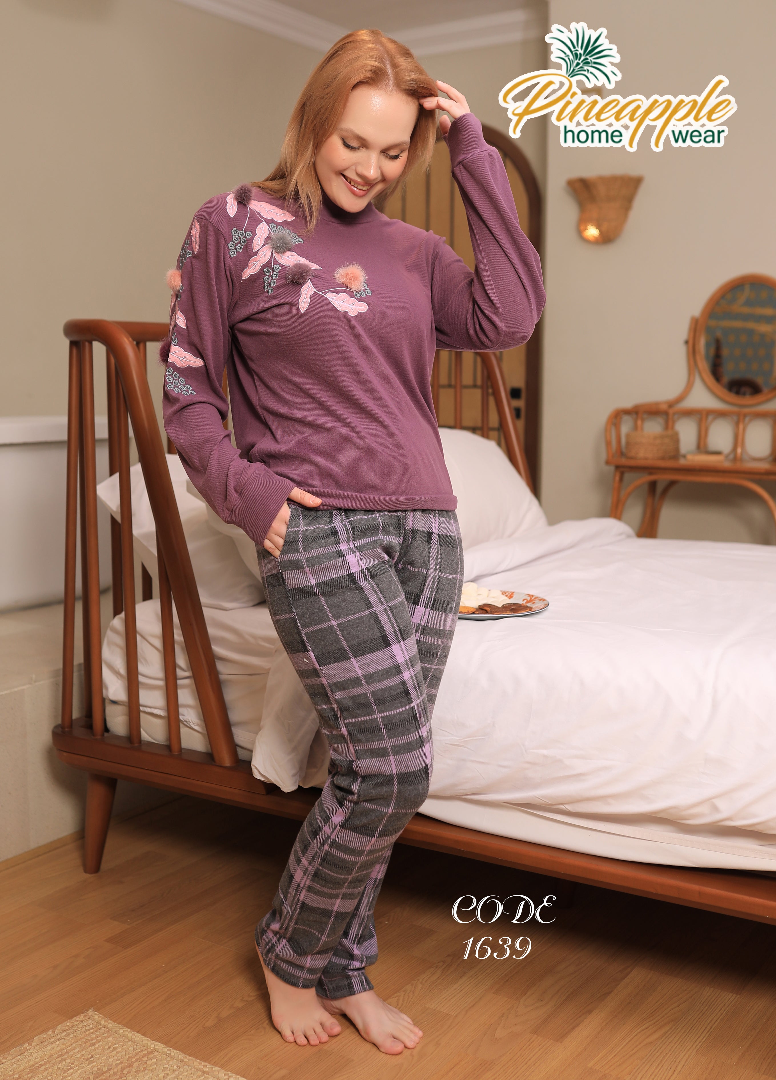 Woman wearing a purple top and plaid pants in a bedroom setting with 'Pineapple Home Wear' branding.