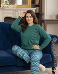 Woman in teal sweater and patterned pants sitting on a blue couch with 'Pineapple Home Wear' branding.