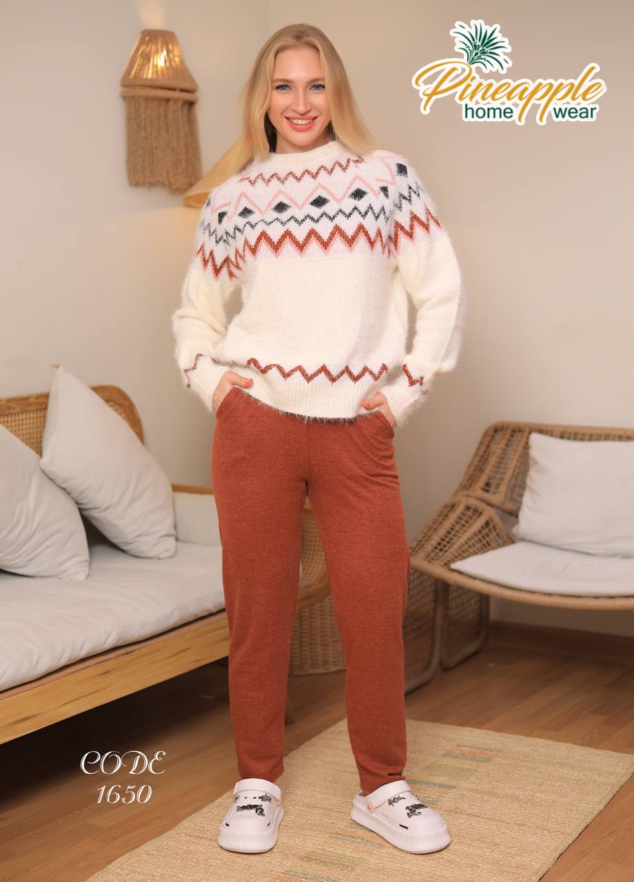 Woman wearing a patterned sweater and red pants in a home setting with 'Pineapple Home Wear' branding.