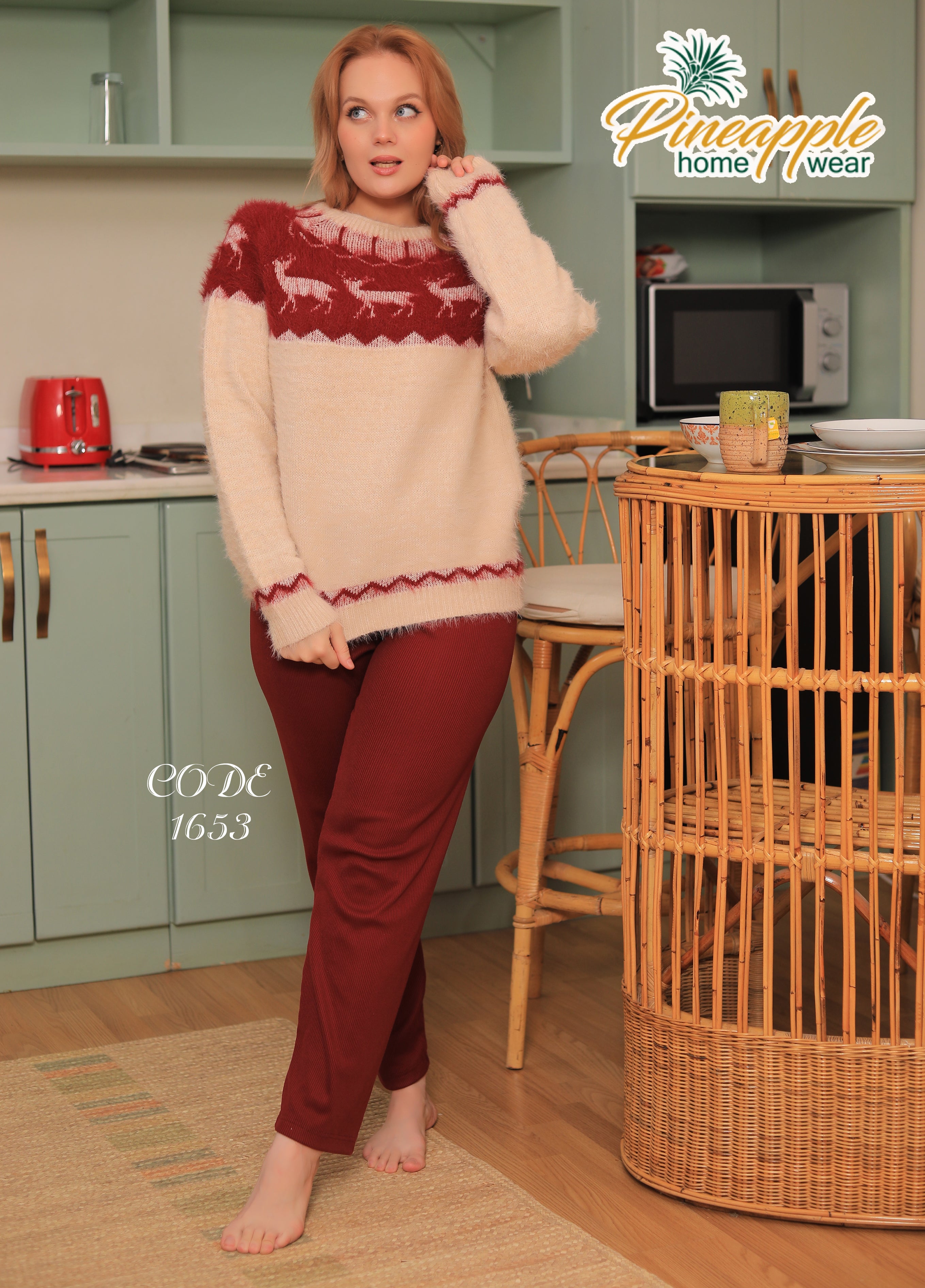 Woman wearing a patterned sweater and red pants in a kitchen setting with 'Pineapple Home Wear' branding.
