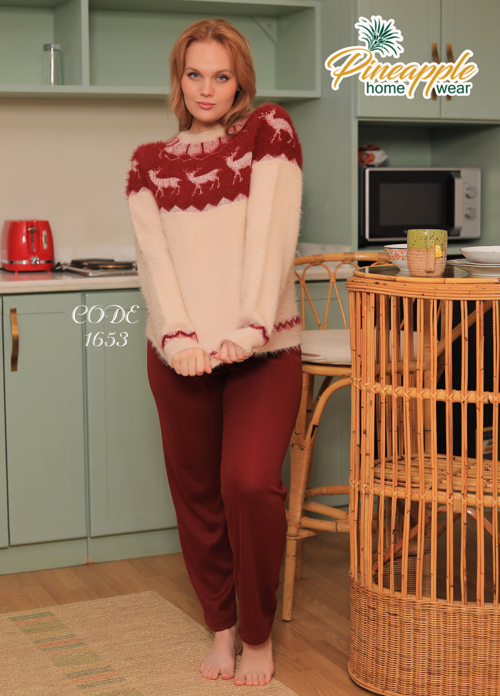 Woman wearing a red and beige sweater with reindeer pattern in a kitchen setting, branded 'Pineapple home wear'.