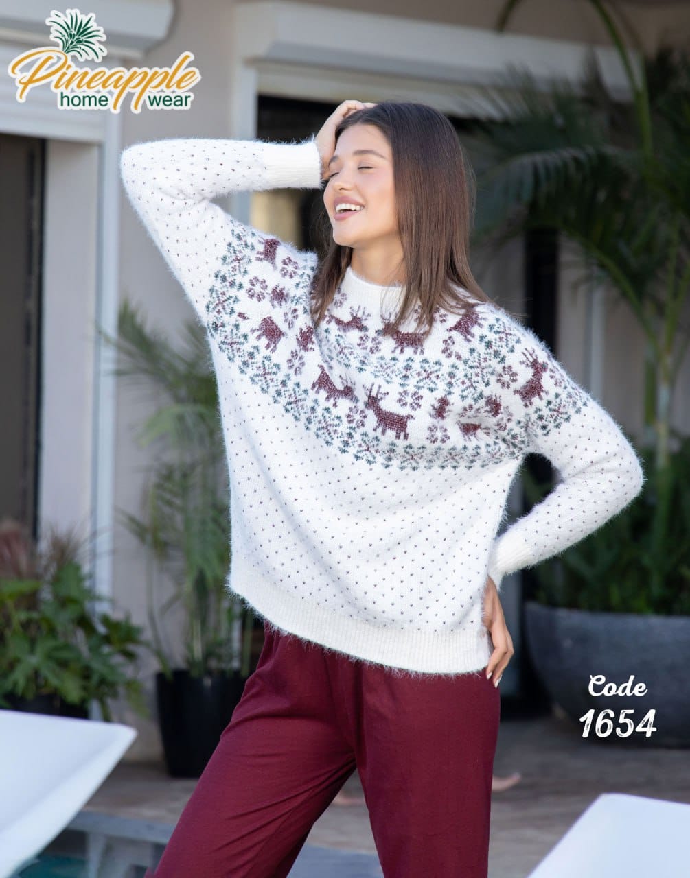Woman wearing a white sweater with deer pattern outdoors, Pineapple Home Wear brand visible