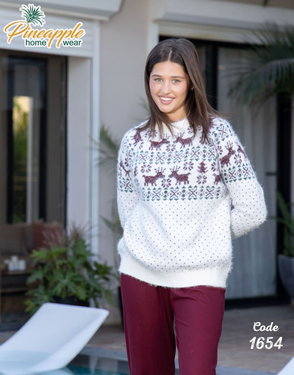 Woman wearing a patterned sweater with reindeer design outdoors, branded 'Pineapple Home Wear'.
