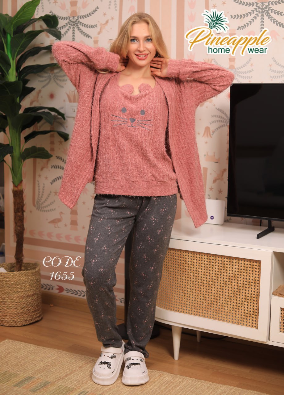Woman wearing a pink sweater and gray pants in a living room setting with 'Pineapple Home Wear' branding.