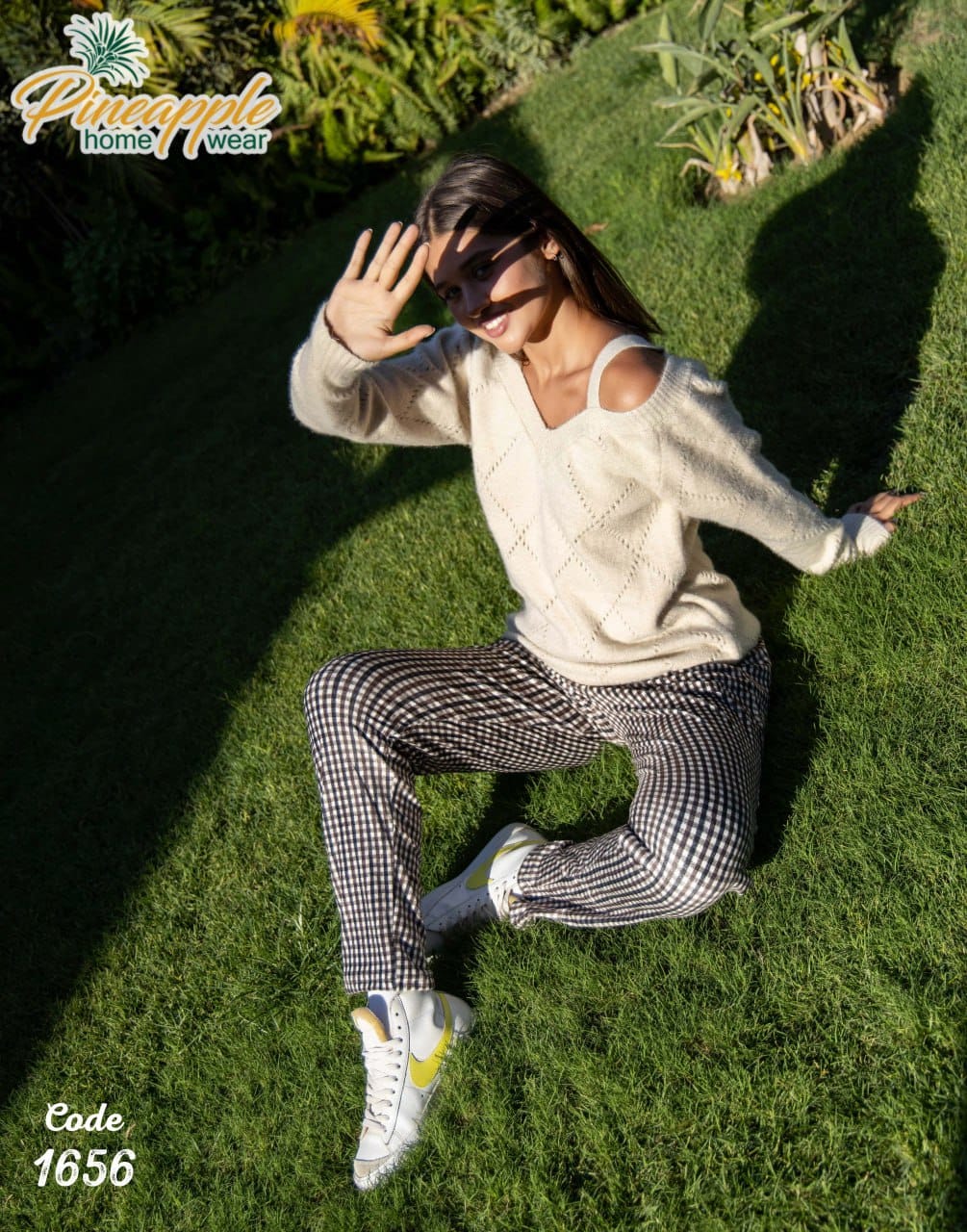Person wearing a white sweater and checkered pants on grass with 'Pineapple Home Wear' branding.