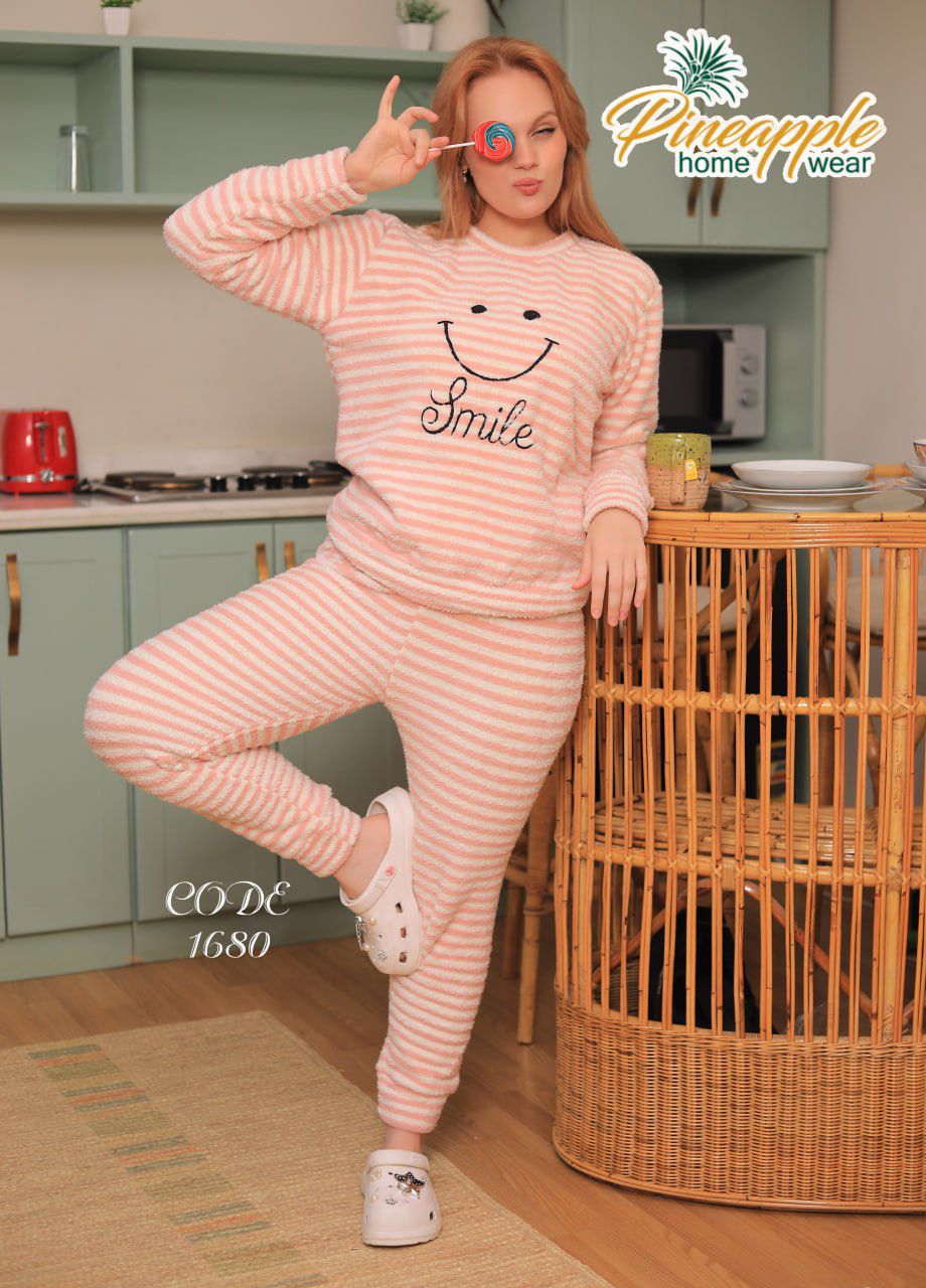 Woman in pink striped pajama set with 'Smile' text in a kitchen, promoting Pineapple Home Wear.