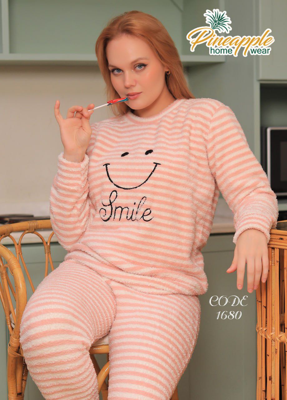 Woman wearing pink striped pajamas with a smiley face design, sitting on a chair.
