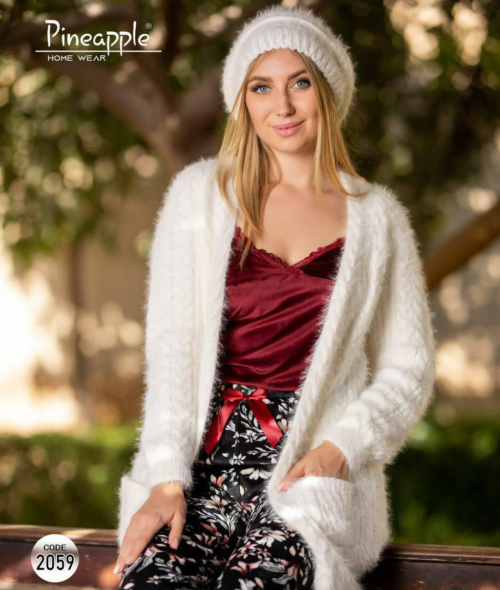 Woman wearing a white cardigan and red top with floral pants, sitting outdoors.