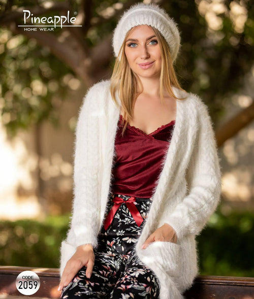 Woman wearing a white cardigan and red top with floral pants, sitting outdoors.
