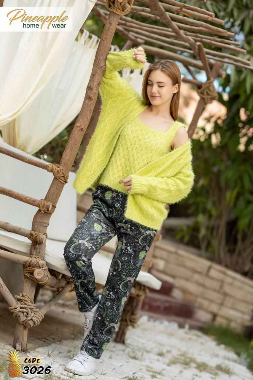 Woman wearing a bright yellow sweater and patterned pants standing in a garden setting.