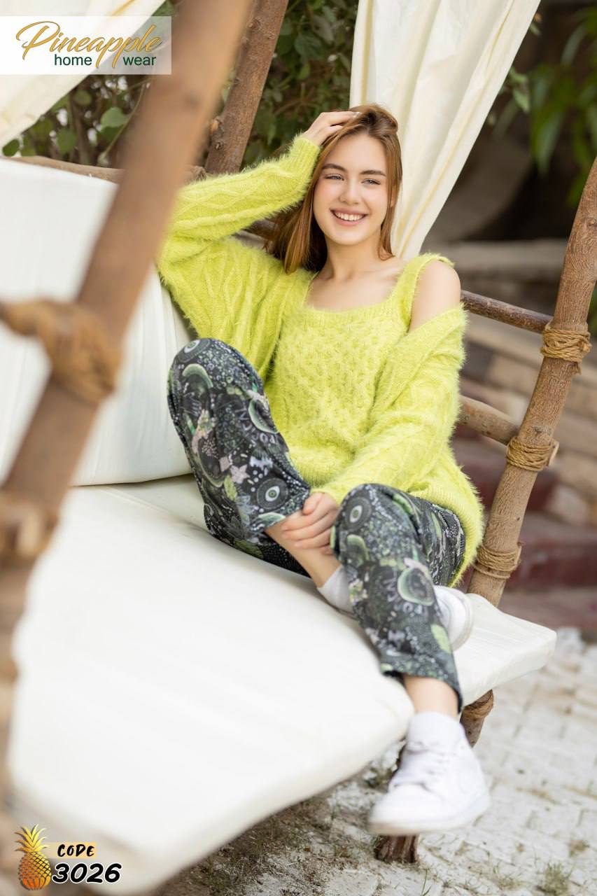 Woman in a bright yellow sweater and patterned pants sitting on a white chair outdoors.
