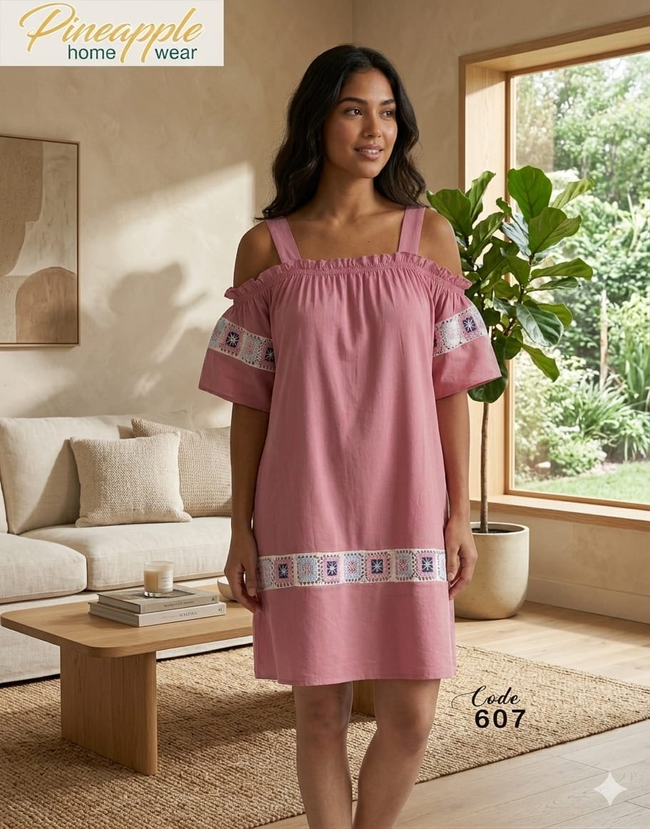 Woman wearing a pink dress with embroidery in a living room setting, with 'Pineapple Home Wear' branding.