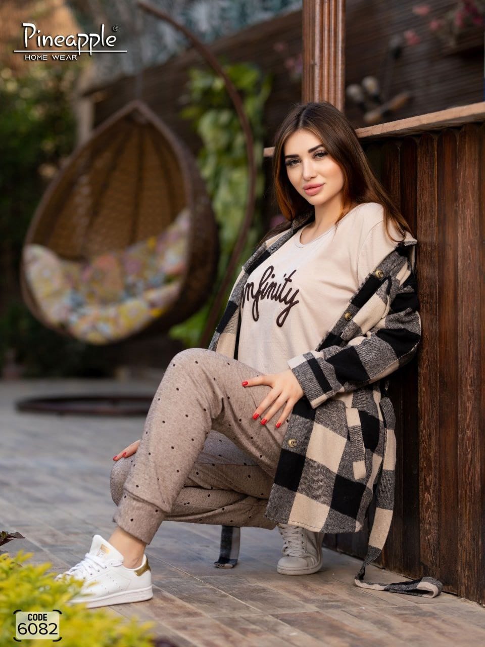 Woman sitting outdoors wearing a checkered coat and beige outfit, with 'Pineapple Home Wear' branding.
