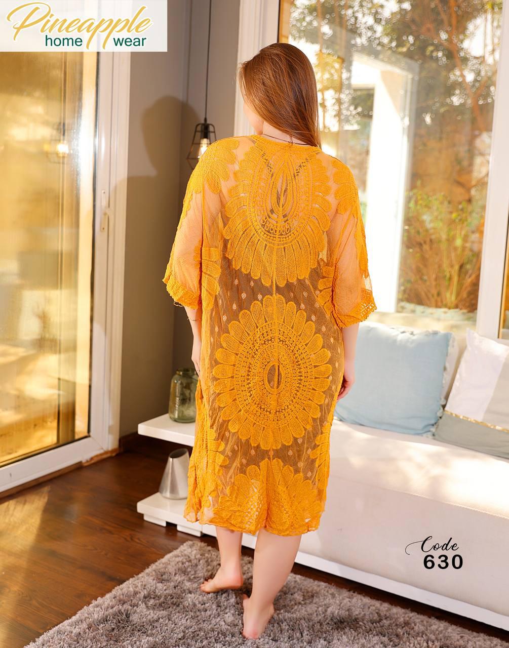 Woman wearing a yellow lace dress standing in a living room.