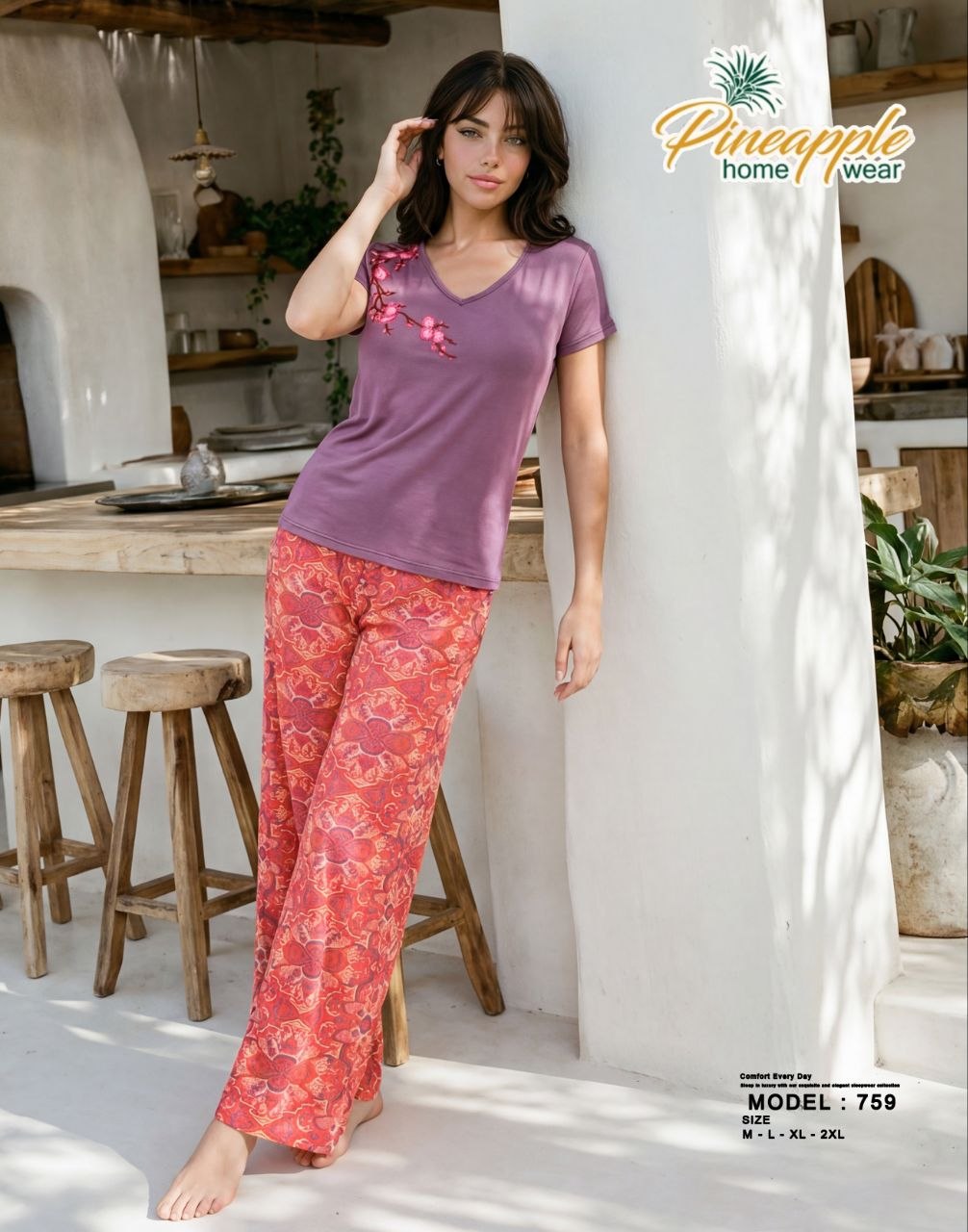 Woman wearing a purple top and red patterned pants in a kitchen setting with 'Pineapple Home Wear' branding.