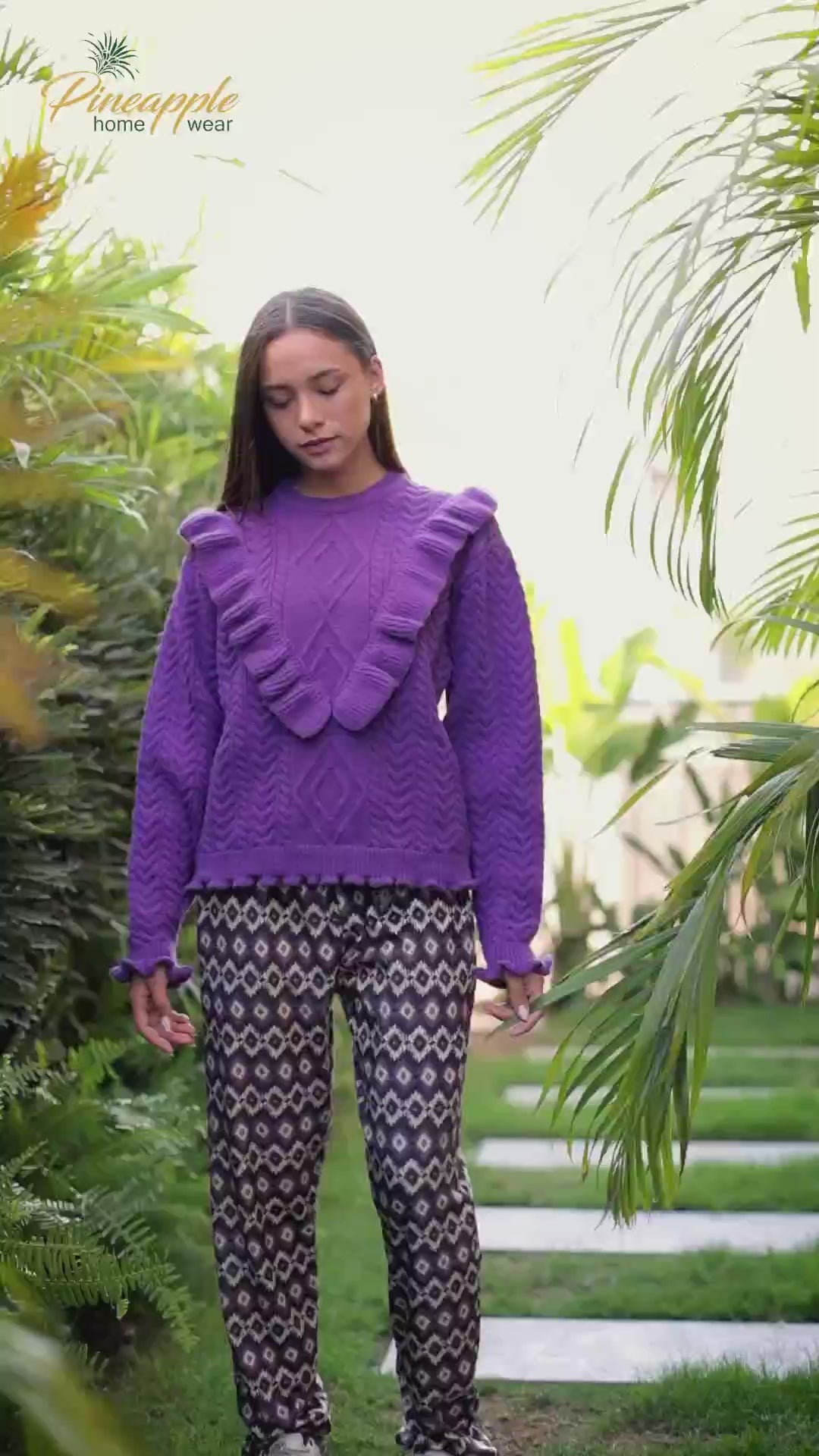Woman wearing a purple sweater and patterned pants with 'Pineapple Home Wear' branding.