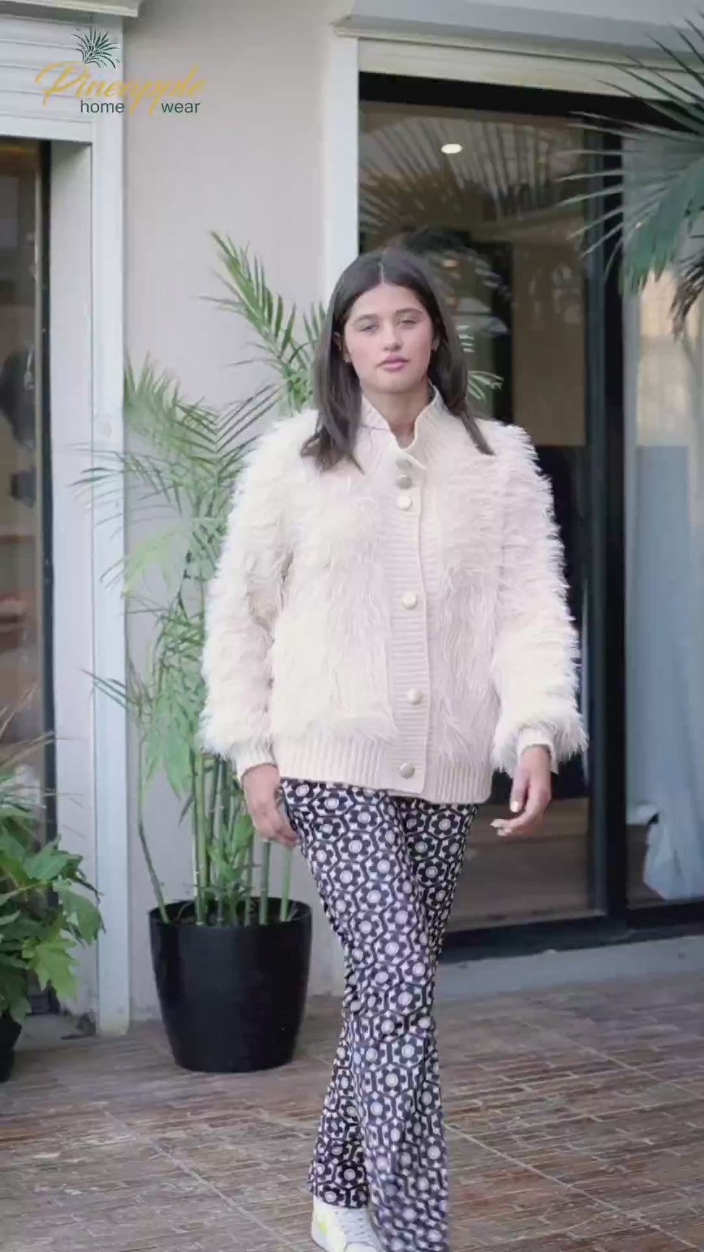 Woman wearing a cream cardigan and patterned pants 