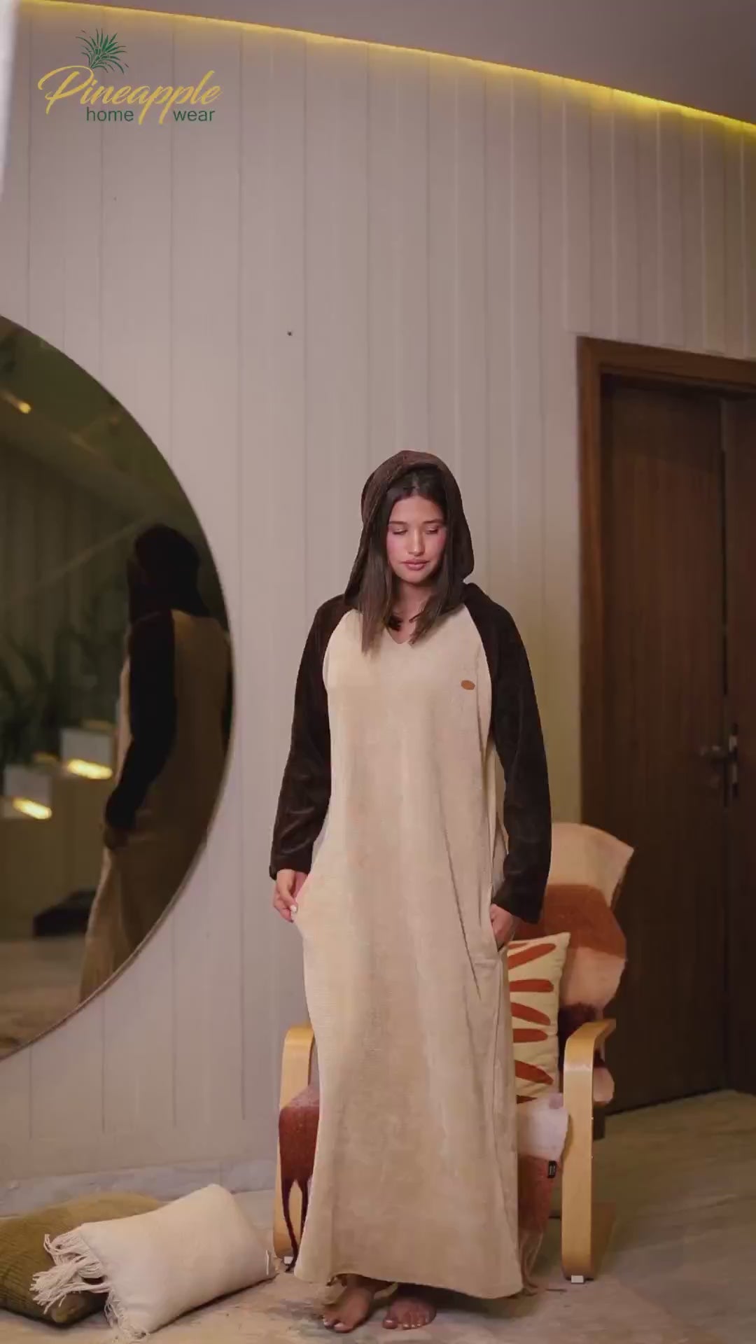 Woman wearing a beige dress with a brown sleeves in a home setting, with 'Pineapple Home Wear' branding.